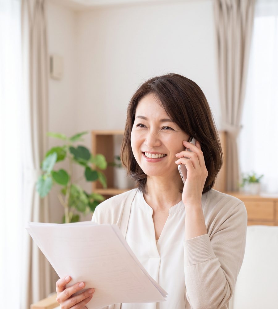 書類を手に、ほっとした表情で笑う女性